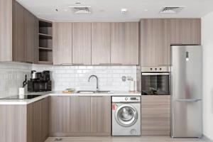 a kitchen with a refrigerator and a washing machine at Silkhaus Modern 1BDR by Emirates Tower Metro in Dubai