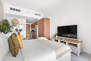 a bedroom with a large white bed and a television at Silkhaus Chic Studio Near Masdar City Park in Yas Island