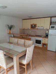 cocina con mesa, sillas y nevera blanca en Apartment Radalj, en Kaštela