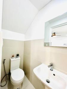 a bathroom with a white toilet and a sink at Artscapes by Kavanah Suites in Batangas City