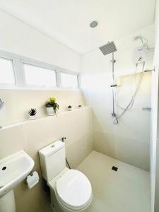 a white bathroom with a toilet and a sink at Artscapes by Kavanah Suites in Batangas City