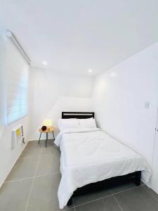 a white bedroom with a bed and a table at Artscapes by Kavanah Suites in Batangas City