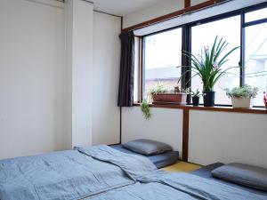 a bedroom with a bed and a window with plants at KOBE coffee hostel in Kobe