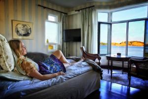 a young girl sitting on a couch in a living room at Hotel Wassilioff - Unike Hoteller in Stavern