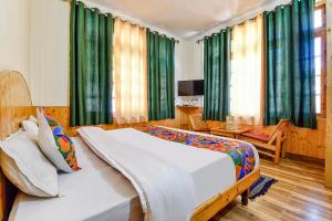 a bedroom with a large bed and green curtains at FabHotel Suvidha Cottage in Manāli