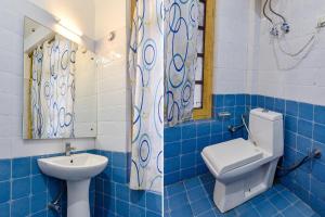a blue tiled bathroom with a toilet and a sink at FabHotel Suvidha Cottage in Manāli