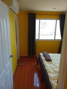 um quarto com paredes amarelas e uma cama com uma janela em HomeState Bang Maprao em Ban Hin Sam Kon