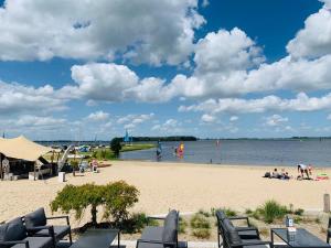 plaża z krzesłami i ludzie bawiący się w wodzie w obiekcie BadHoophuizen 6-per Bungalow Veluwemeer Trampoline w mieście Hulshorst