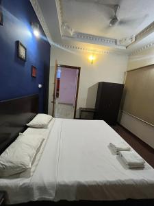 a bedroom with a large white bed and a blue wall at THE ALP HOTEL Bypass Road in Madurai