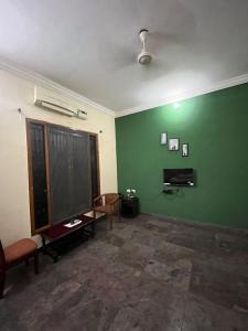uma sala de estar com uma parede verde e uma cadeira em THE ALP HOTEL Bypass Road em Madurai