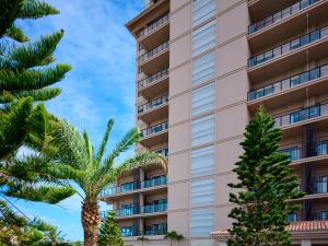 a tall building with palm trees in front of it at Hotel Shigira Mirage Beach Front in Miyako Island