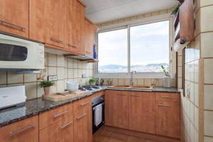 a kitchen with wooden cabinets and a large window at City View Penthouse - 2 Bedroom Suite in Barcelona