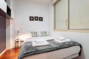 a white bedroom with a bed with two pillows at Plaça Catalunya Incredible 3bedroom Duplex with Balcony in Barcelona