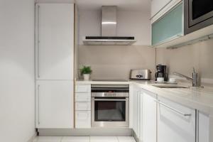 cocina con armarios blancos y horno de acero inoxidable en 3bedroom Duplex with balcony in plaza Cataluña, en Barcelona