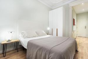 een witte slaapkamer met een groot bed en een tafel bij Bright and modern 2bedroom in Las Ramblas 2 1A in Barcelona