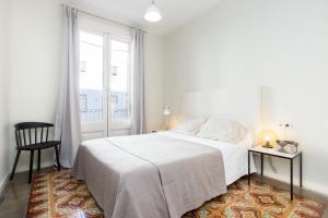 4 bedroom apartment with a balcony in Las Ramblas 2 2 في برشلونة: غرفة نوم بيضاء بها سرير ونافذة