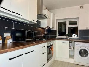 a kitchen with white cabinets and a washing machine at Cosy 4 Bed House in Aldershot