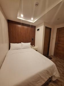 a bedroom with a large white bed with a wooden headboard at Casa Ison Hotel in Sablayan