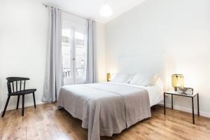 Centric 2bedroom in Las Ramblas 3 1A في برشلونة: غرفة نوم بيضاء بسرير وكرسي
