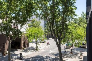 una strada cittadina con alberi e gente per strada di Poblenou renovated 3BD next to the beach a Barcellona