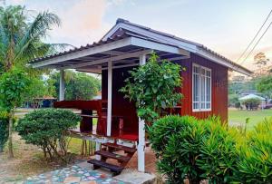 uma pequena casa vermelha com um banco à frente em ผาผึ้ง Neverland em Ban Wang Krathon (1)