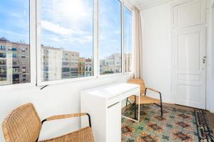 um quarto com uma secretária, cadeiras e janelas em Historic Catalan 4BD apartment in Gran Vía em Barcelona