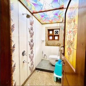 ein Bad mit einem WC und einer bemalten Wand in der Unterkunft Opal Oasis Villa in Alībāg