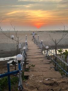 a man walking down a wooden walkway on the beach at Absolute paradise in Gokarna