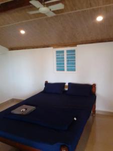 a bedroom with a bed with blue pillows and a window at Absolute paradise in Gokarna