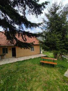 eine Holzbank, die im Gras vor einem Gebäude sitzt in der Unterkunft Valley Tara in Plužine