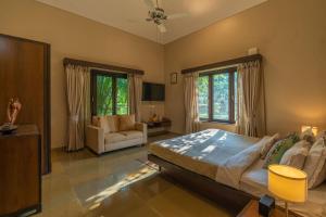 um quarto com uma cama grande e uma sala de estar em Moksh Villa by StayVista - Amidst of orchards, with a pool, gazebo, and indoor games em Alibaug