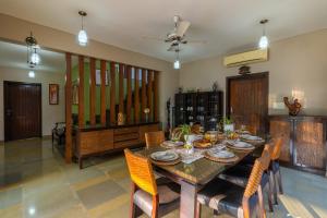 a dining room with a wooden table and chairs at StayVista at Moksh Villa - BBQ & Jacuzzi in Alibaug +34 photos