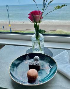 een bord met een chocoladedessert en een vaas met een roos bij Hotel No5, Beachfront with Free Private Car Park in Llandudno