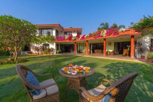a patio with chairs and a table in a yard at StayVista at Moksh Villa - BBQ & Jacuzzi in Alibaug