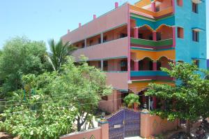 um edifício colorido com árvores em frente em Rainbow Guest House em Tiruvannamalai