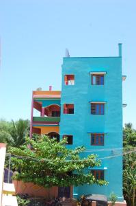 un edificio azul con un árbol delante de él en Rainbow Guest House en Tiruvannāmalai