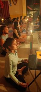 eine Gruppe von Menschen, die in einem Zimmer mit Kerzen sitzen in der Unterkunft swaastik stay in Rishikesh