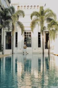 a woman standing in front of a building with palm trees at Reservoir Hotels in Siem Reap
