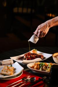 a person holding a spatula over a table with plates of food at JW Marriott Hotel Kolkata in Kolkata