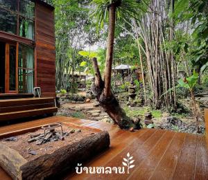 a wooden deck with a tree trunk next to a house at MayamYay Privacy Homestay @Mea Nea Chiang Dao in Chiang Dao