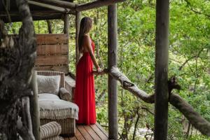 a woman in a red dress standing on a porch at Summerfields Rose Retreat and Spa in Hazyview