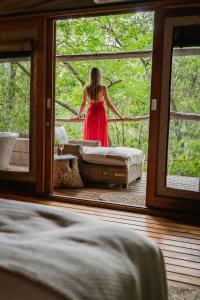 a woman in a red dress looking out of a window at Summerfields Rose Retreat and Spa in Hazyview