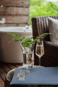a vase and a glass on a table with a book at Summerfields Rose Retreat and Spa in Hazyview