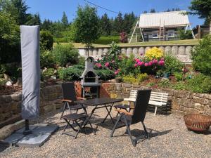 a table and chairs and a grill in a garden at Ferienwohnungen Fertsch in Sonneberg