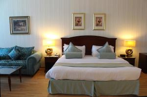um quarto de hotel com uma cama grande e um sofá em Swiss International Al Hamra Hotel em Dammam