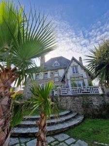 una casa grande con palmeras delante en Villa Fresquet en Cherbourg en Cotentin