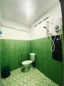 uma casa de banho com WC numa sala de azulejos verdes em Abot guest house em Kuala Tahan