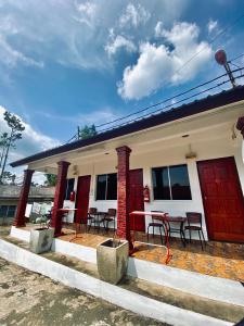 ein Haus mit roten Türen sowie einem Tisch und Stühlen in der Unterkunft Abot guest house in Kuala Tahan