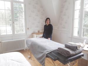 a woman standing next to a bed in a room at Manoir de Camblain in Camblain-lʼAbbé