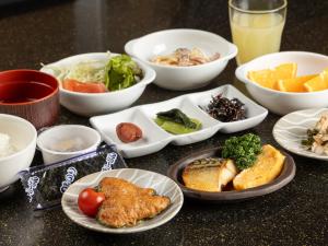 a table with plates of food and bowls of food at Tabist Hirosaki Touei Hotel in Hirosaki